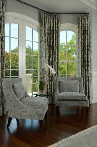 photo of pair of modern upholstered chairs in front of complementary window treatments