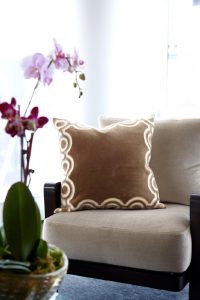 detail photo of upholstered chair and custom designed pillow in neutral colors