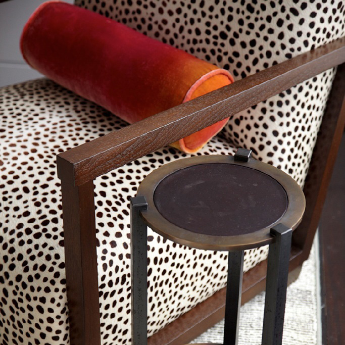 photo of cylinder orange accent pillow on animal print upholstered chair
