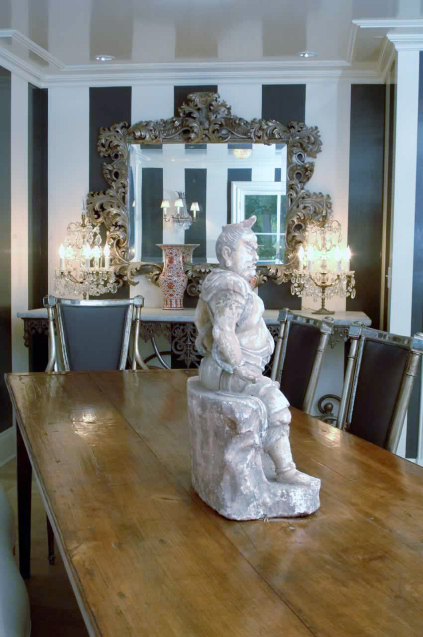 detail photo of dining room table with Buddha statue and ornate mirror