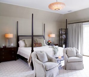 photo of bedroom with muted natural color palette, four poster bed and a pair of upholstered chairs