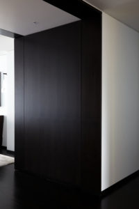 Contemporary entry with floor to ceiling dark wood doors that are closed