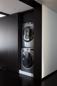 Contemporary entry with floor to ceiling dark wood doors that are open revealing washer and dryer